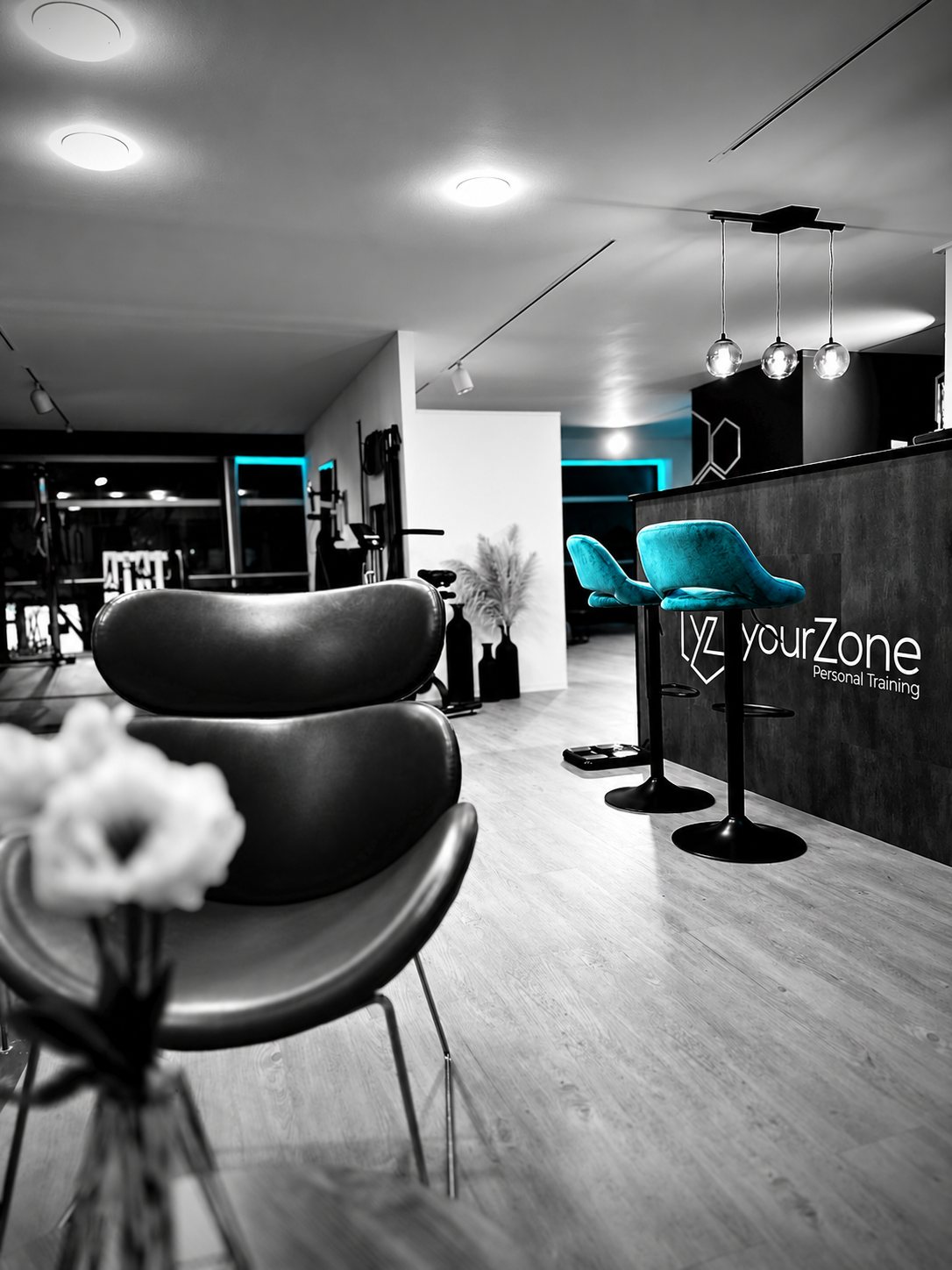 Sitzbereich und yourZone-Theke in Schwarz-Weiß mit zwei türkisfarbenen Barhockern